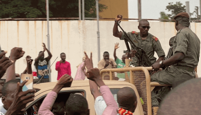 "Citizens hailing two military men on a military vehicle"