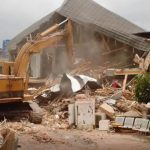 Excavator breaking down a house