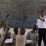 "A teacher in front of a classroom"