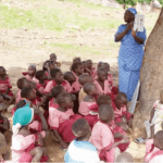 School children learning under a tree
