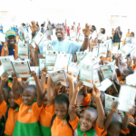 Pupils displaying exercise books donated by AKISAN in Uyo