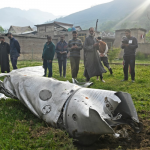 People look at a fuel tank of an aircraft in Wuyan, near Srinagar, on May 7, 2025. India and Pakistan exchanged heavy artillery along their contested frontier on May 7, after New Delhi launched missile strikes on its arch-rival in a major escalation between the nuclear-armed neighbours. New Delhi announced it had carried out “precision strikes at terrorist camps” at nine sites in Pakistan-administered Kashmir, days after it blamed Islamabad for a deadly attack on the Indian-run side of the disputed region. (Photo by Tauseef MUSTAFA / AFP)