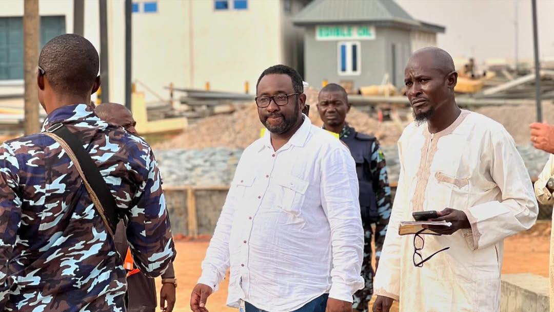 Amadu Sule in a white shirt, standing between a police officer and a man in cream kaftan